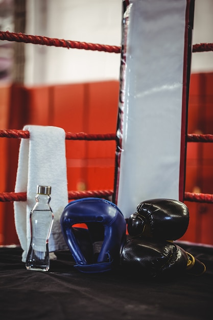 Guantes de boxeo, tocados, botella de agua y una toalla en el ring de boxeo