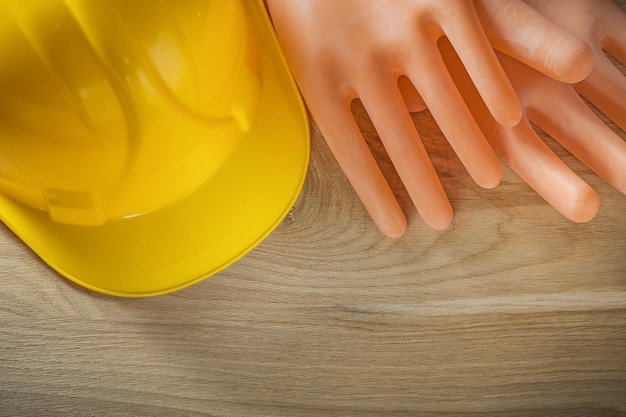 Guantes dieléctricos casco sobre tabla de madera.