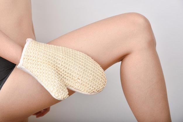 Guantes de exfoliación Masaje de cepillado en seco para anticelulítico y flujo linfático Mujer frotando la piel de las piernas