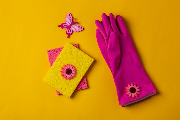 Guantes de goma y esponjas a la espera de lavarse sobre un fondo amarillo