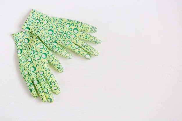 Guantes de goma para trabajos de jardinería sobre fondo blanco. Preparación para la temporada de siembra. Enfoque selectivo.