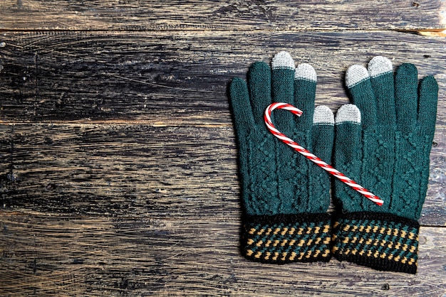 Guantes de invierno y bastón de caramelo sobre fondo de madera. Decoración navideña