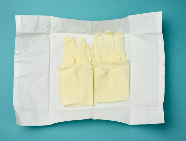 guantes médicos blancos estériles en papel blanco sobre un fondo azul