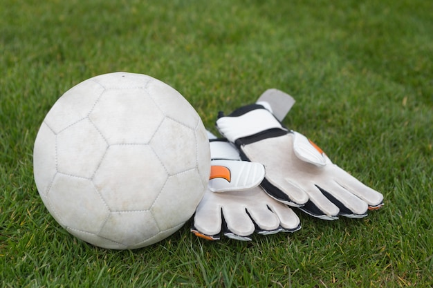 Guantes de portero y fútbol en campo