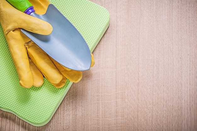 Guantes de protección pala de mano de metal espuma jardinería almohadilla de rodillas en tablero de madera concepto de agricultura