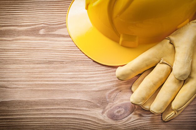 Guantes protectores de casco de construcción amarillo en concepto de construcción de tablero de madera