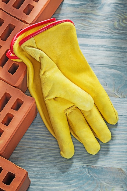 Guantes protectores de cuero de ladrillos rojos en el concepto de construcción de la vista superior del tablero de madera.