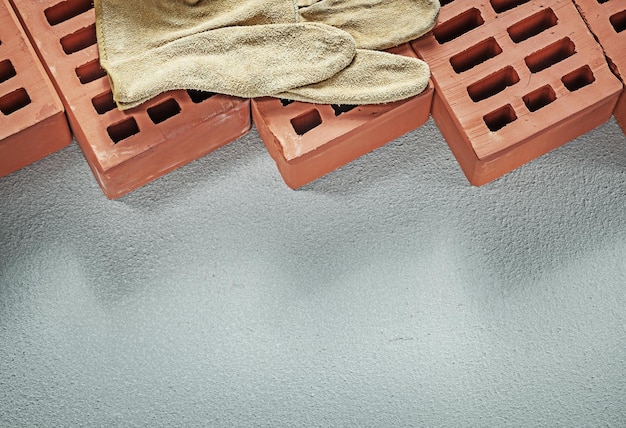 Guantes protectores de cuero de ladrillos rojos sobre el concepto de construcción de superficies de hormigón.