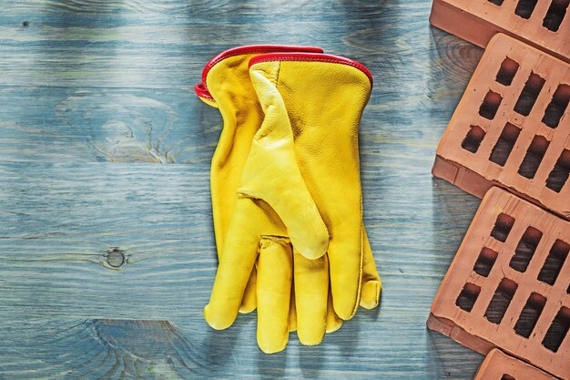 Guantes protectores ladrillos rojos en concepto de construcción de tablero de madera