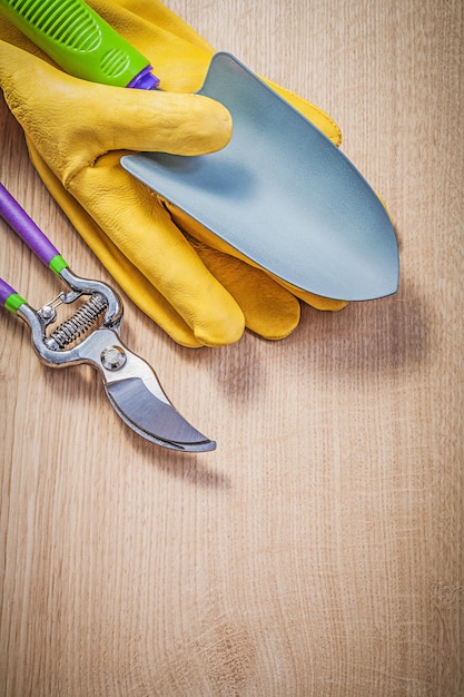 Guantes protectores mano pala tijeras de podar en tablero de madera concepto de jardinería