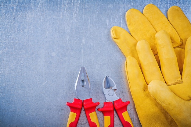 Guantes de seguridad de cuero alicates pinzas en concepto de electricidad de fondo metálico