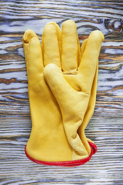 Foto guantes de seguridad de cuero amarillo sobre tabla de madera.