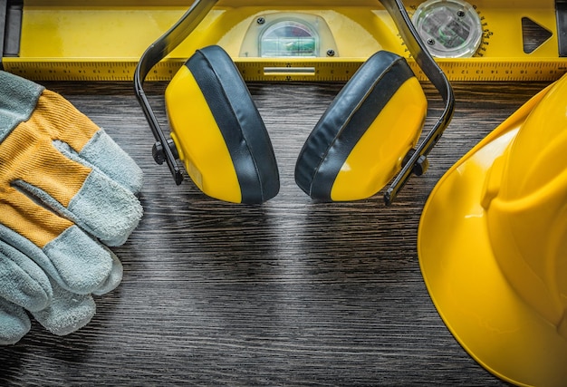 Guantes de seguridad de nivel de construcción construyendo orejeras de casco en tablero de madera