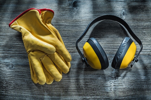 Guantes de seguridad orejeras en tablero de madera.