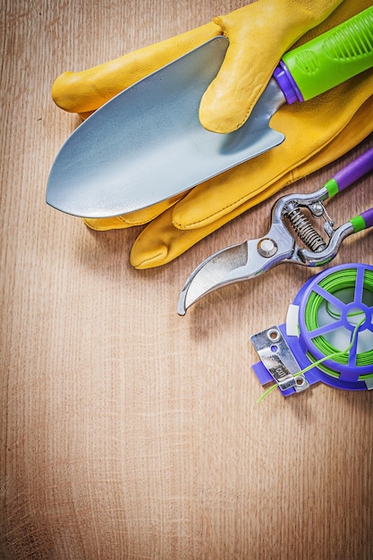 Guantes de seguridad, pala de mano, tijeras de podar, corbata de giro suave en el concepto de jardinería de tablero de madera