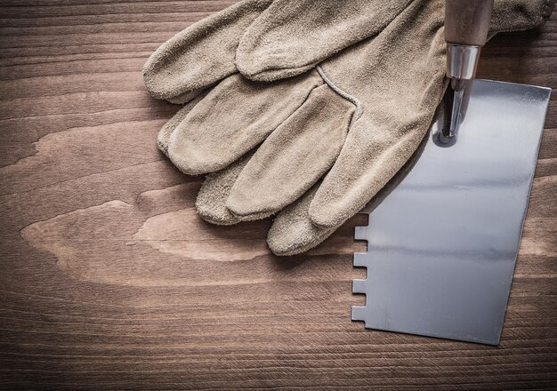 Guantes de trabajo y masilla sobre tablero de madera.