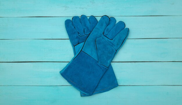 Guantes de trabajo sobre fondo de madera azul. Vista superior