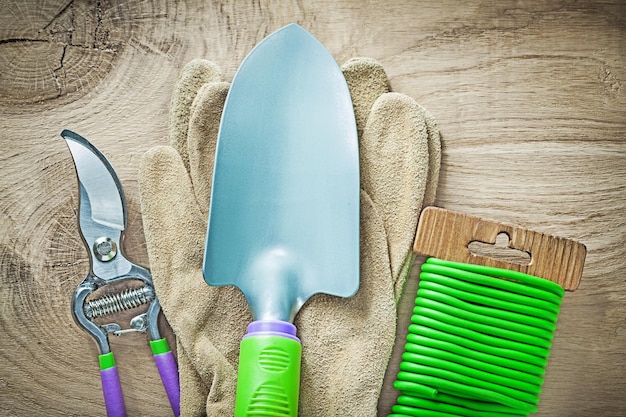 Guantes de trabajo, tijeras de podar, pala de mano, amarre de alambre blando en tablero de madera, concepto de jardinería.