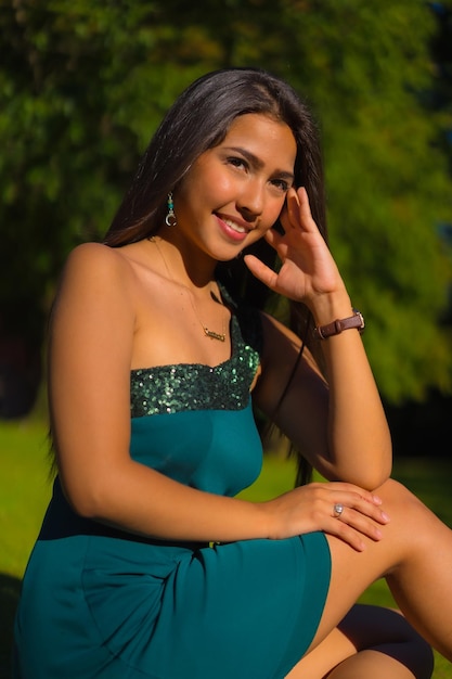 Una guapa joven latina morena con el pelo largo y liso con un vestido verde ajustado