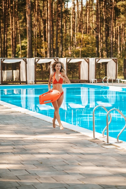 Una guapa salvavidas corriendo cerca de la piscina.