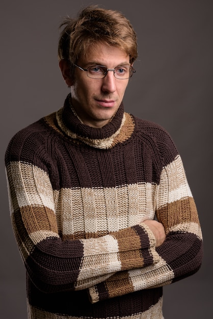 Guapo con anteojos contra la pared gris