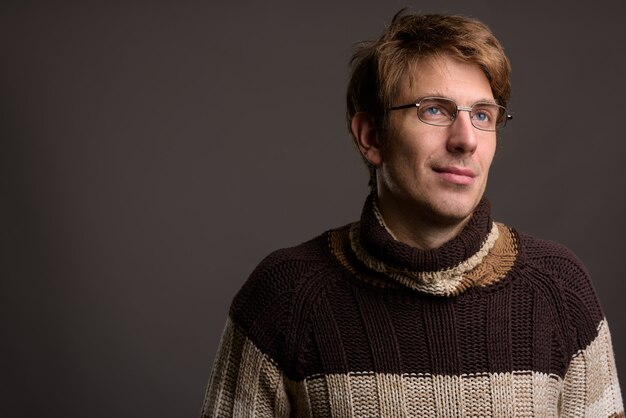 Guapo con anteojos contra la pared gris