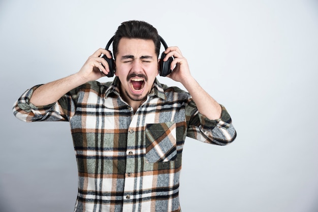 guapo en auriculares de pie y escuchando la canción.