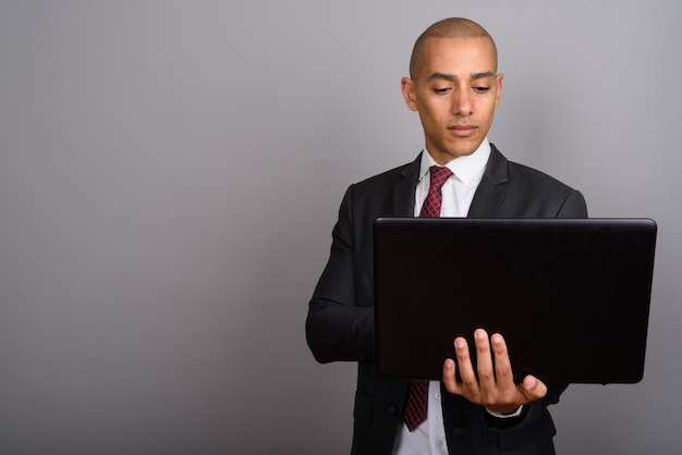 guapo, calvo, hombre de negocios, llevando, traje, con, computador portatil, en, gris