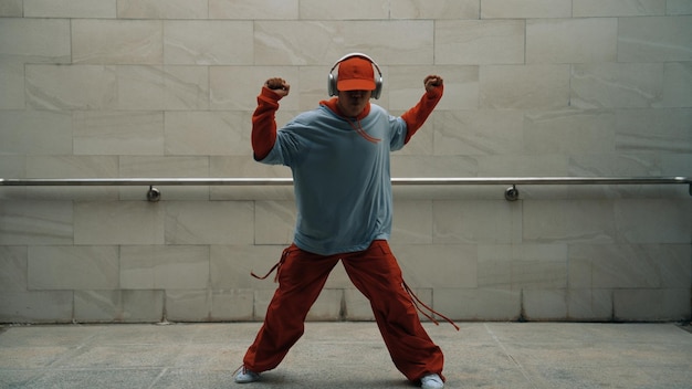 El guapo coreógrafo practica el baile callejero en un fondo gris.