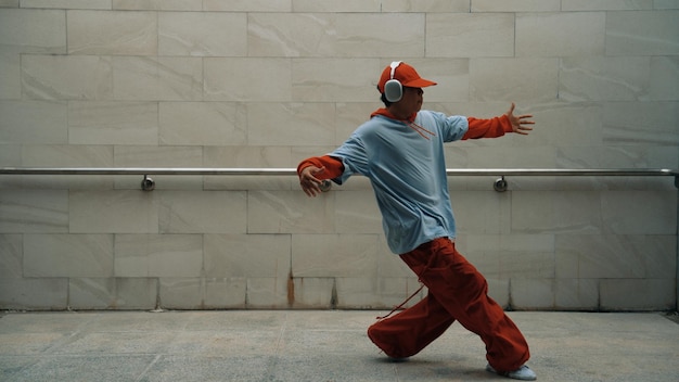 El guapo coreógrafo practica el baile callejero en un fondo gris.