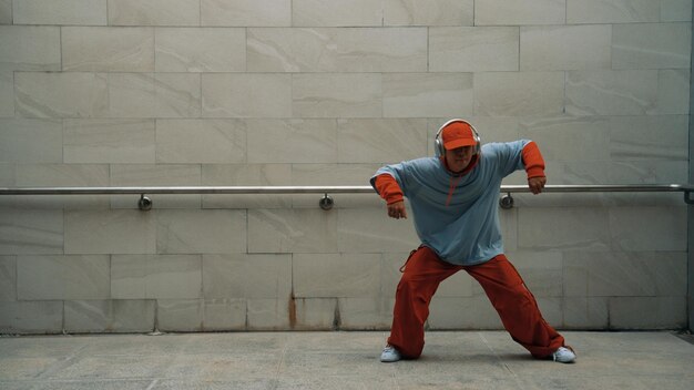 El guapo coreógrafo practica el baile callejero en un fondo gris.