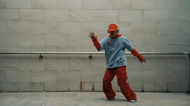 El guapo coreógrafo practica el baile callejero en un fondo gris.