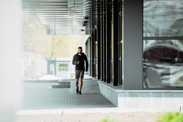 Un guapo deportista corriendo cerca del edificio.