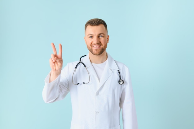 Guapo doctor hombre vestido con abrigo y estetoscopio sobre fondo azul aislado