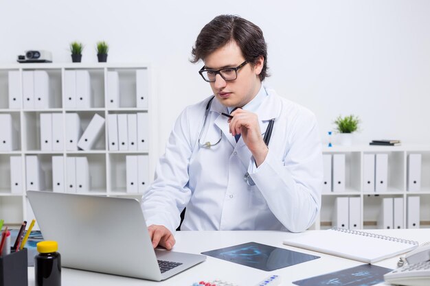 Guapo doctor usando laptop