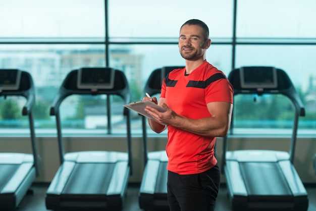 Guapo Entrenador Personal Con Un Portapapeles En El Gimnasio Y Flexionando Los Músculos Muscular Atlético Culturista Fitness Modelo