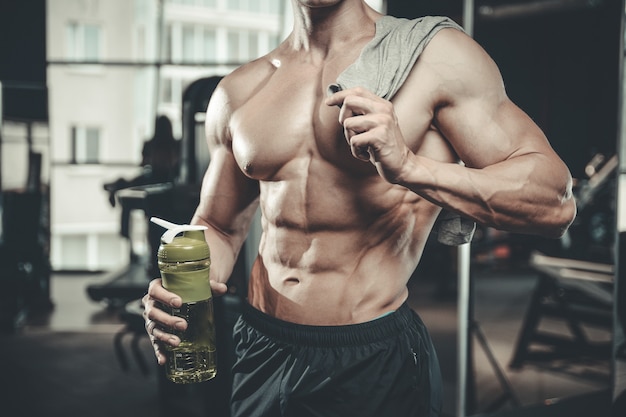 Guapo fisicoculturista poderoso en el gimnasio