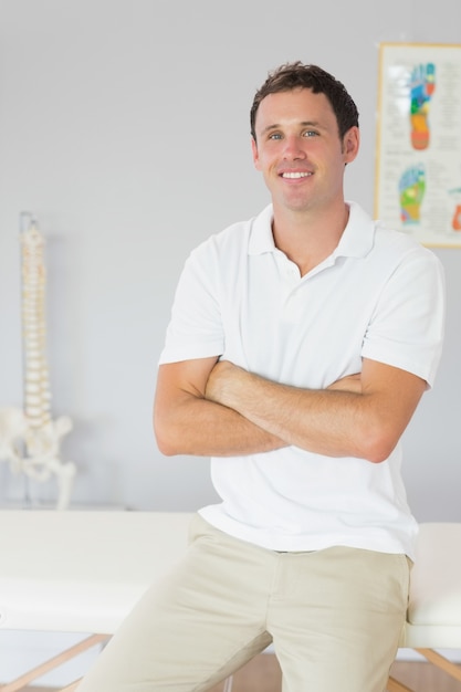 Foto guapo fisioterapeuta feliz sentado con los brazos cruzados