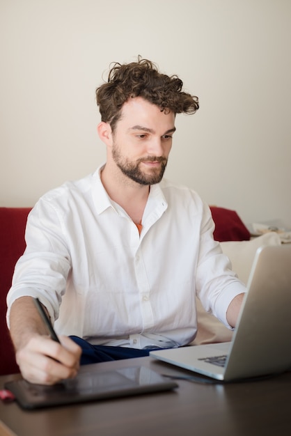 guapo hipster moderno hombre trabajando en casa usando la computadora portátil