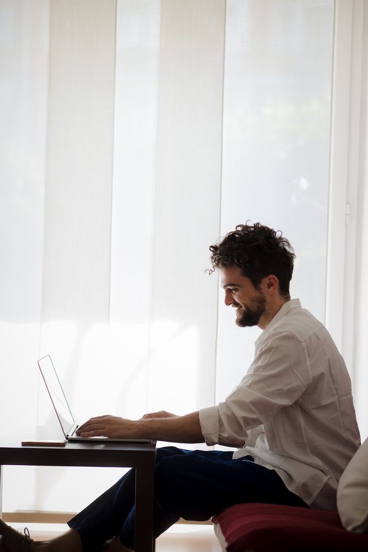 Foto guapo hipster moderno hombre trabajando en casa usando la computadora portátil