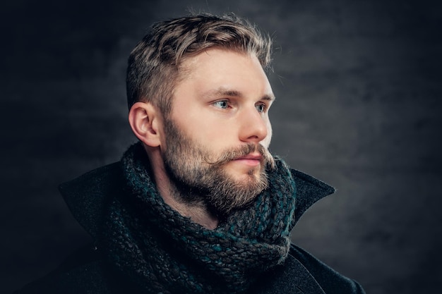 Guapo hombre barbudo con una chaqueta de lana y una bufanda.