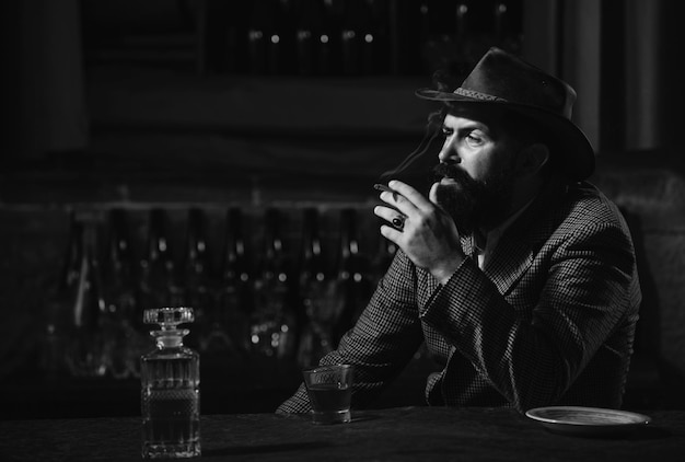 Guapo hombre barbudo disfrutando de whisky en bar hipster con barba bebiendo un brandy en bar tipo brutal