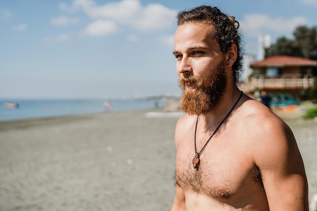 Guapo hombre barbudo con el torso desnudo en la playa