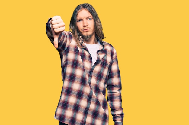 Guapo hombre caucásico con el pelo largo con camisa hipster que parece infeliz y enojado mostrando rechazo y negativo con el pulgar hacia abajo gesto mala expresión