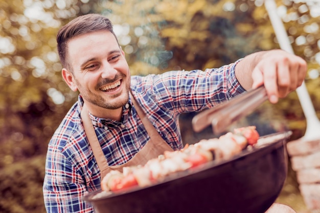 Foto guapo hombre feliz preparando barbacoa al aire libre