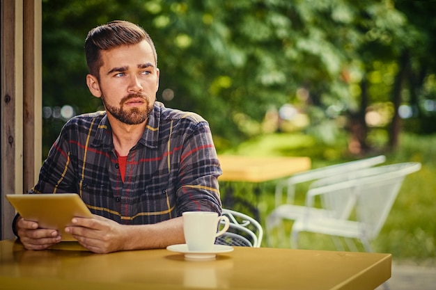 Guapo hombre hipster barbudo usando una computadora portátil en un café.