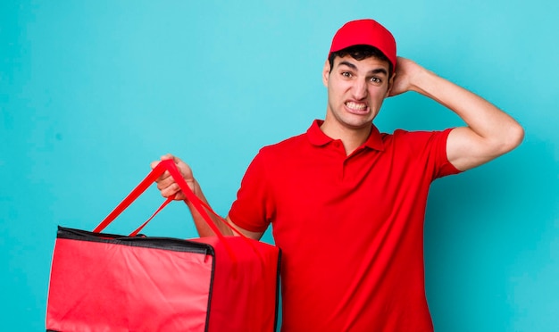 Guapo hombre hispano que se siente estresado ansioso o asustado con las manos en la cabeza concepto de entrega de pizza