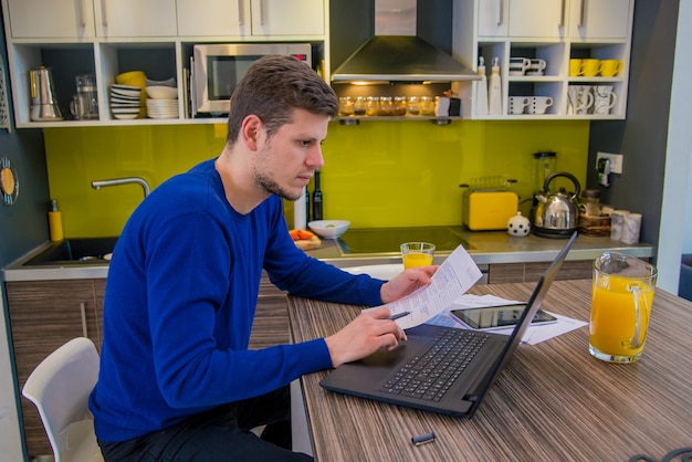 Guapo hombre moderno diseñador de trabajo en casa usando la computadora portátil en casa. Hombre feliz trabajando desde casa usando la tableta digital y portátil