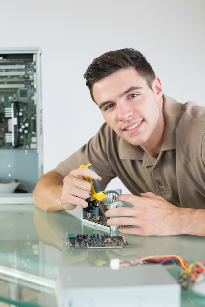 Foto guapo ingeniero informático alegre reparación de hardware con alicates