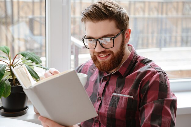 Guapo joven barbudo leyendo libros.